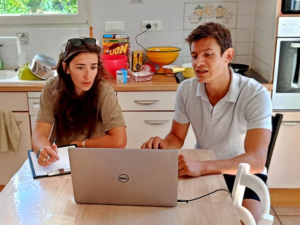 Séance à domicile dans une cuisine : Simon explique, la cliente prend des notes